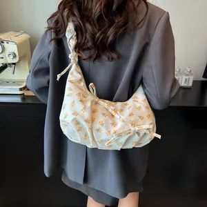 Floral print shoulder bag in cream with bow detail and pleats shown on a model