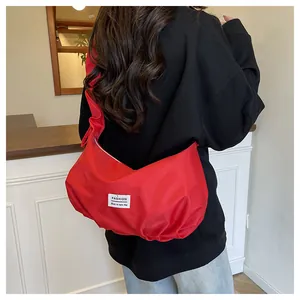 Détail du sac baguette en nylon rouge plissé avec étiquette blanche sur modèle