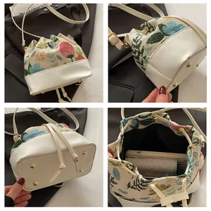 Detail view of floral canvas bucket bag with drawstring and golden protective feet