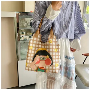 Close-up of a brown plaid canvas tote featuring a cute cartoon girl and floral print