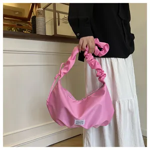 Détail du sac hobo plissé rose clair avec une étiquette fashion en décor de café