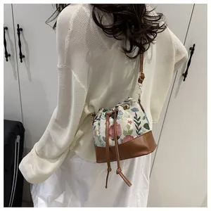 Detail of the vintage floral jacquard bucket bag with brown leather base and drawstring