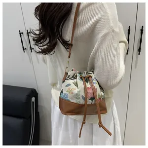 Detail of vintage floral embroidery bucket bag with brown leather drawstring straps
