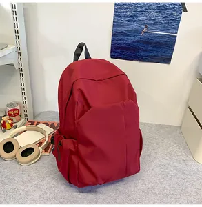 Détail du sac à dos rouge minimaliste en toile avec poche avant cachée sur un bureau