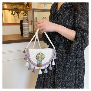 Dettaglio di borsa tessuta bohémien con perline colorate, ricami e nappe con frange viola