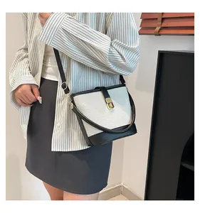Detalle del bolso cubo en contraste con tejido trenzado crema y ribete de cuero negro