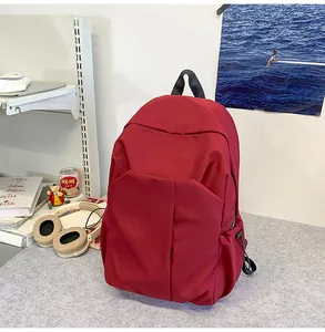 Sac à dos rouge minimaliste avec poches latérales sur un bureau pour vie étudiante
