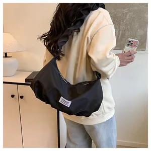 Détail du sac baguette noir avec bandoulière à volants présenté sur un mannequin