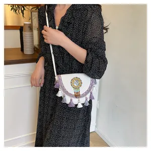 Dettaglio di borsa boho intrecciata con perline colorate e nappe viola