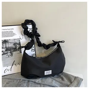 Détail d'un sac noir à bandoulière froncée avec une étiquette de marque minimaliste