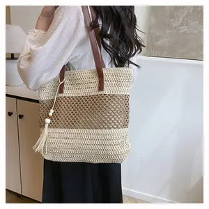 Detalle del bolso tote de paja a rayas con correas de cuero y borla de cuentas