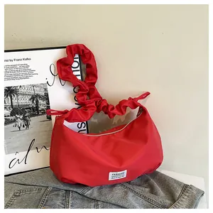 Détail du sac croissant rouge avec bandoulière plissée et étiquette de mode sur nylon