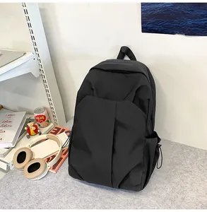 Détail d'un sac à dos noir minimaliste montrant la grande poche avant et le cordon latéral