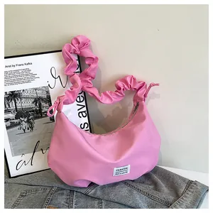 Détail du sac baguette rose avec bandoulière plissée et étiquette de mode sur denim
