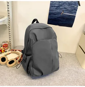 Vue détaillée du sac à dos gris en nylon avec poches latérales à cordon sur un bureau