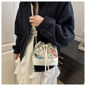 Detail of floral drawstring bucket bag with gold hooks and white pleated skirt outfit