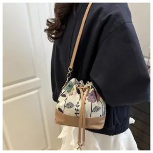 Detail of printed fabric bucket bag with leather bottom and drawstring closure