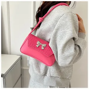 Close-up of bright pink woven shoulder bag featuring a silver bow metal buckle detail