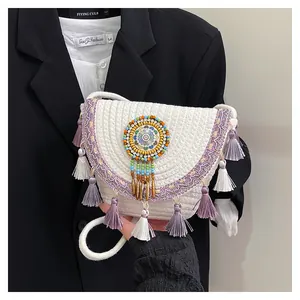 Dettaglio della borsa in paglia intrecciata bianca con nappe viola e ricami di perline