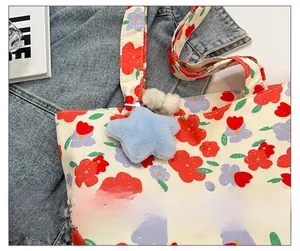 Close-up of floral canvas tote bag featuring a blue star plush charm and soft pom-poms