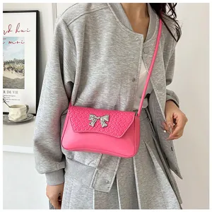 Detail of rose pink woven PU leather shoulder bag with a silver metallic bow decoration