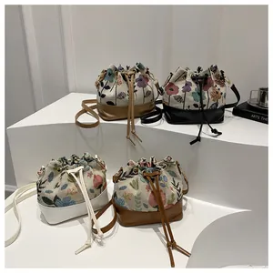 Detailed arrangement of four floral drawstring bucket bags on a white tiered display