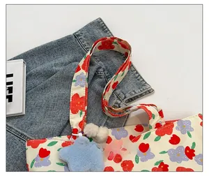 Detail of floral canvas tote bag showing wide comfortable straps and star plush charm