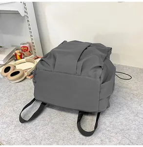 Vue détaillée d'un sac à dos plissé gris foncé dans un décor de bureau chaleureux