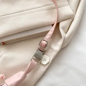 Detalle de la correa de cuero rosa con hebilla ajustable y adorno de flor blanca