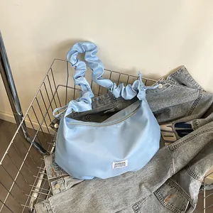 Sac baguette bleu clair avec bandoulière plissée dans un panier en métal