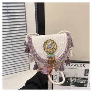 Dettaglio borsa boho in corda con nappe viola e un ciondolo decorativo di perline