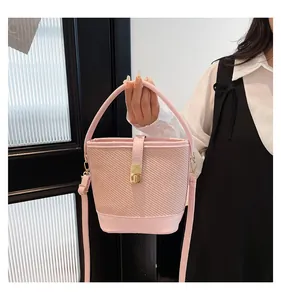 Detail of light pink bucket bag with woven texture, golden twist lock and round handle