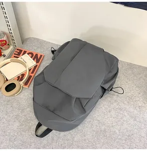 Sac à dos gris foncé minimaliste présenté avec des accessoires pour ordinateur et ville