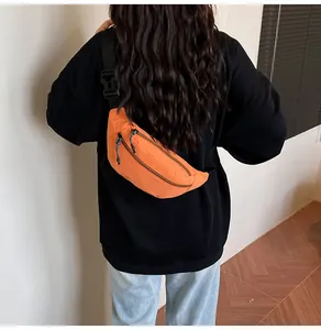 Detail of bright orange waterproof waist bag with double zippers and black adjustable strap