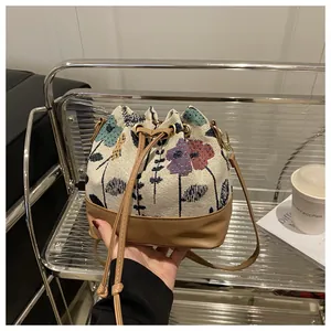 Detail of drawstring bucket bag with floral jacquard fabric and brown leather base