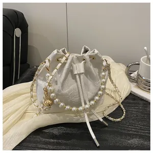 Detail van witte kant emmertas met parel handvat en gouden hanger op stoffen ondergrond