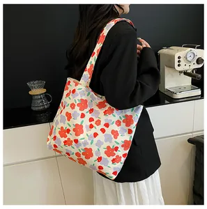 Lifestyle view showing a large canvas tote bag with vibrant floral patterns on the shoulder