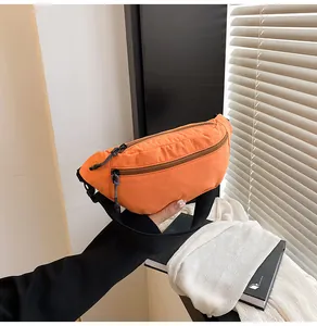 Close-up of durable orange nylon waist bag with double zippers and black strap