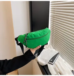 Detail showing the adjustable black nylon strap and green fabric texture of this waist bag