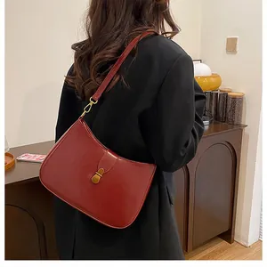 Detailed side view of deep red underarm bag on model showcasing size and glossy PU leather