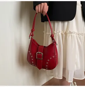 Detail of red crescent shoulder bag featuring metal eyelets and knotted strap detail