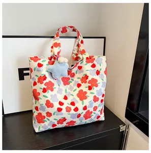 Close-up of floral canvas tote bag featuring a blue star plush keychain and red flower pattern