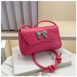 Detail of fuchsia shoulder bag with woven flap texture and silver bow accent