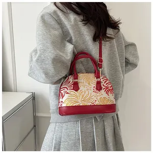 Close-up of vintage shell-shaped handbag with red embroidery and golden hardware