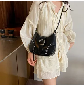 Close-up of black matte leather shoulder bag with silver buckle and studs on model