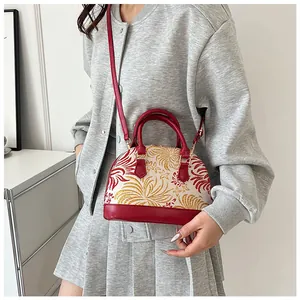 Detailed close-up of shell-shaped bag featuring red and white floral fabric and leather strap