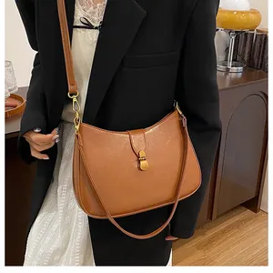 Close-up of caramel leather crescent bag featuring a vintage gold metal twist lock buckle