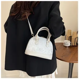 Detail of off-white shell handbag featuring elegant jacquard pattern and leather strap