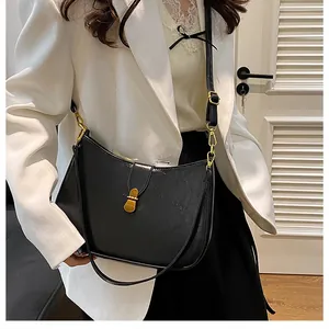 Close-up of black glossy leather moon bag with adjustable strap and gold buckle detail