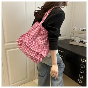 Détail d'un sac cabas en toile à carreaux roses avec des volants portés à l'épaule